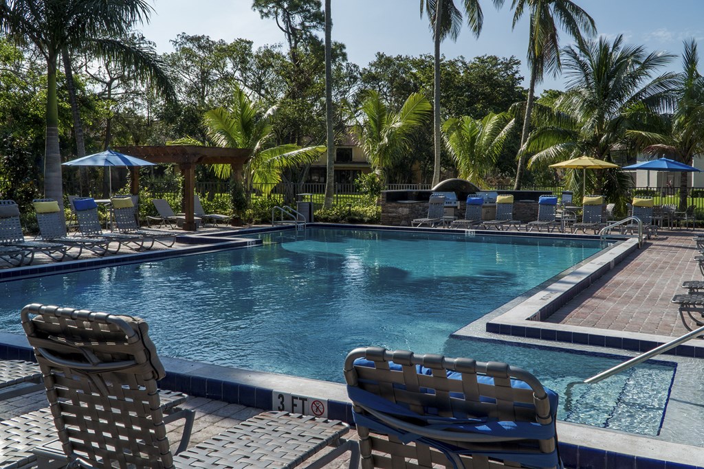 a swimming pool with chairs and umbrellas at a resort