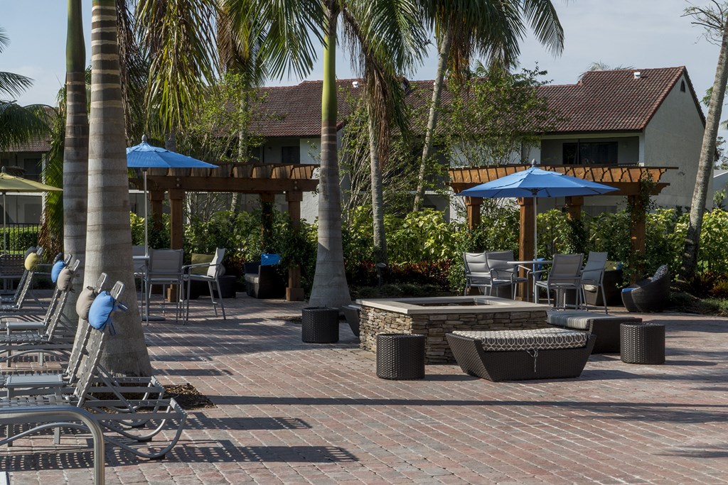 a patio with tables and chairs and palm trees