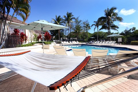 a large pool with hammocks and chairs around it