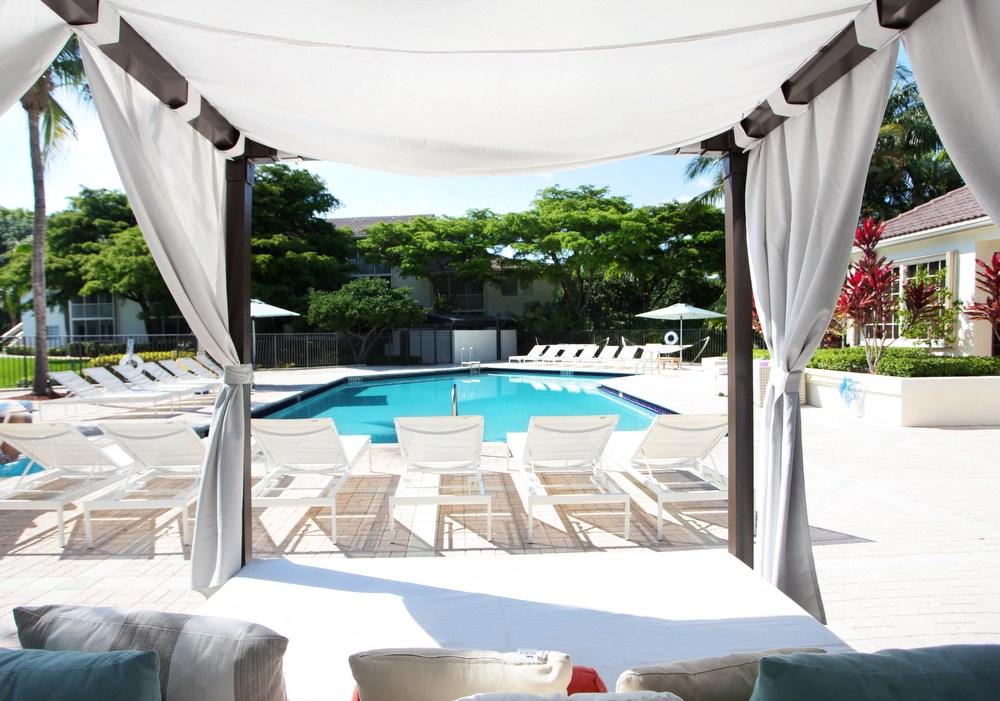 a large swimming pool with white chairs and a canopy