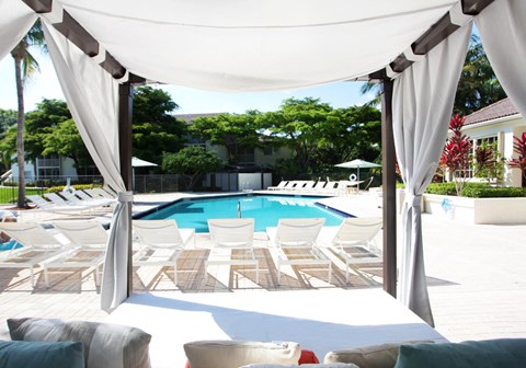 a large swimming pool with white chairs and a canopy