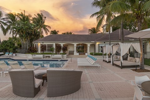 a swimming pool with chairs and umbrellas in front of a house