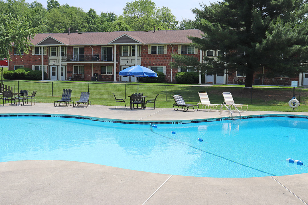 a swimming pool with chairs and umbrellas in front of a building