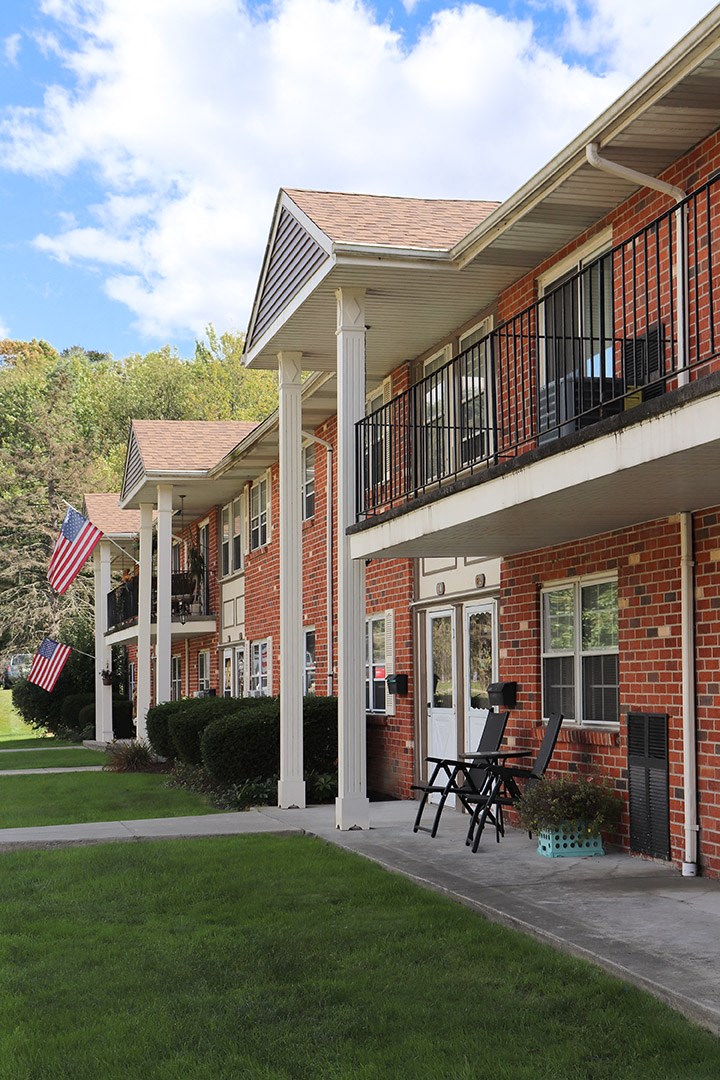 a view of the front porch of a brick building with a balcony and a flag