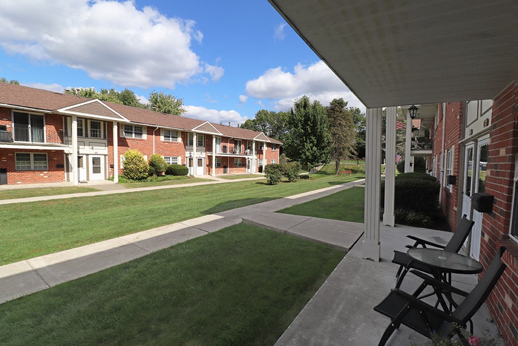 a patio with a table and chairs in front of an apartment building