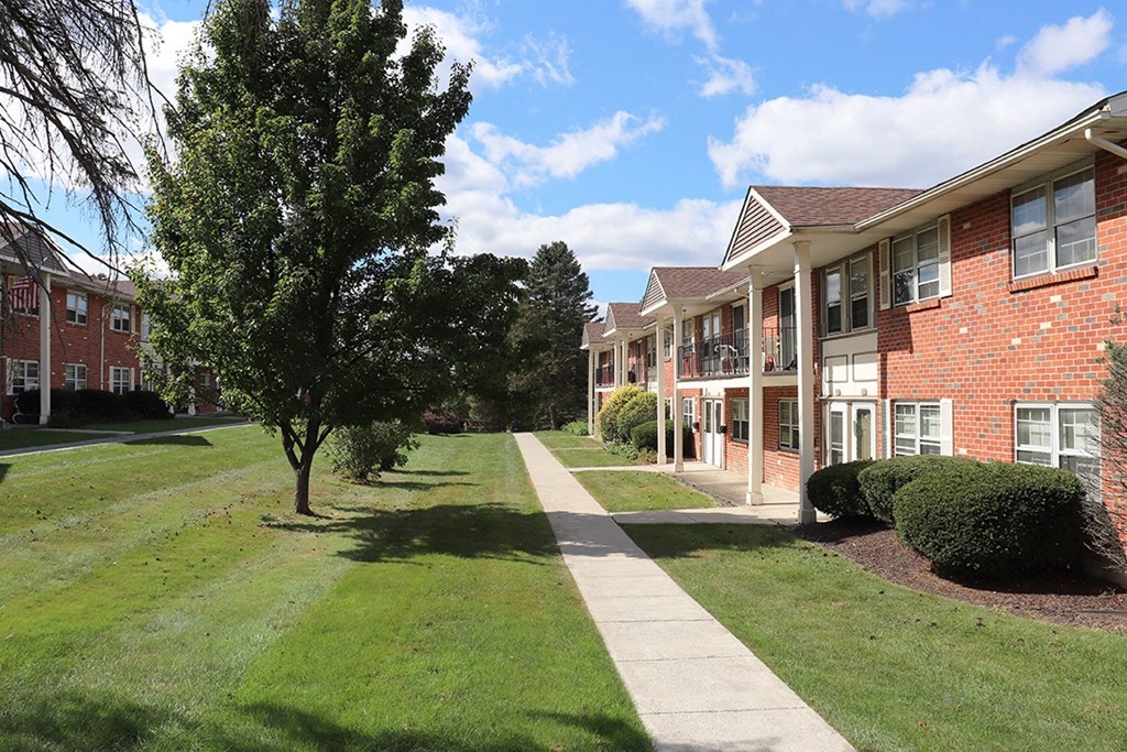 a sidewalk in front of a brick apartment building