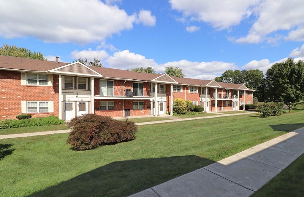 an exterior view of an apartment building with a lawn and sidewalk