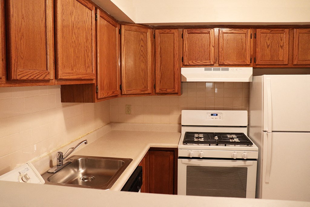 a kitchen with wooden cabinets and white appliances and a sink