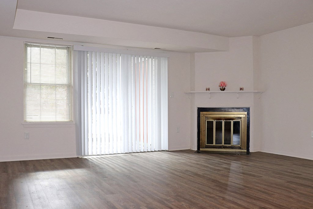 an empty living room with a fireplace and blinds