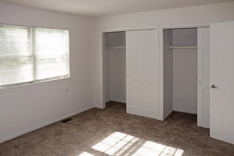 an empty bedroom with a closet and a window