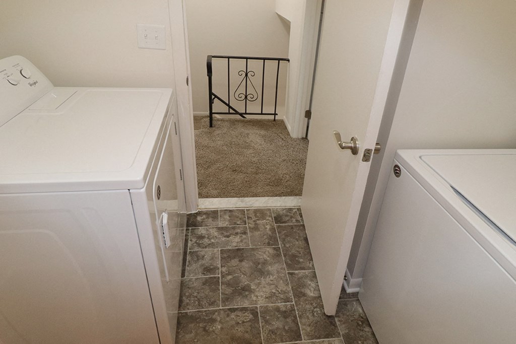 a laundry room with a washer and dryer and a door to a hallway