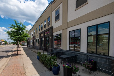 the side of a building with tables and chairs on the sidewalk