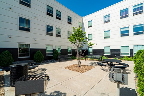 an outside patio area with tables and benches in front of a white building