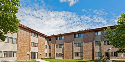 A large brick building with a green lawn in front.