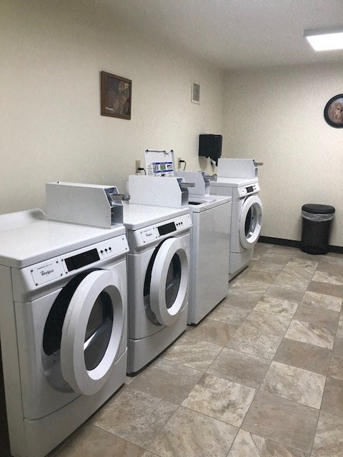 four washing machines are lined up in a laundromat
