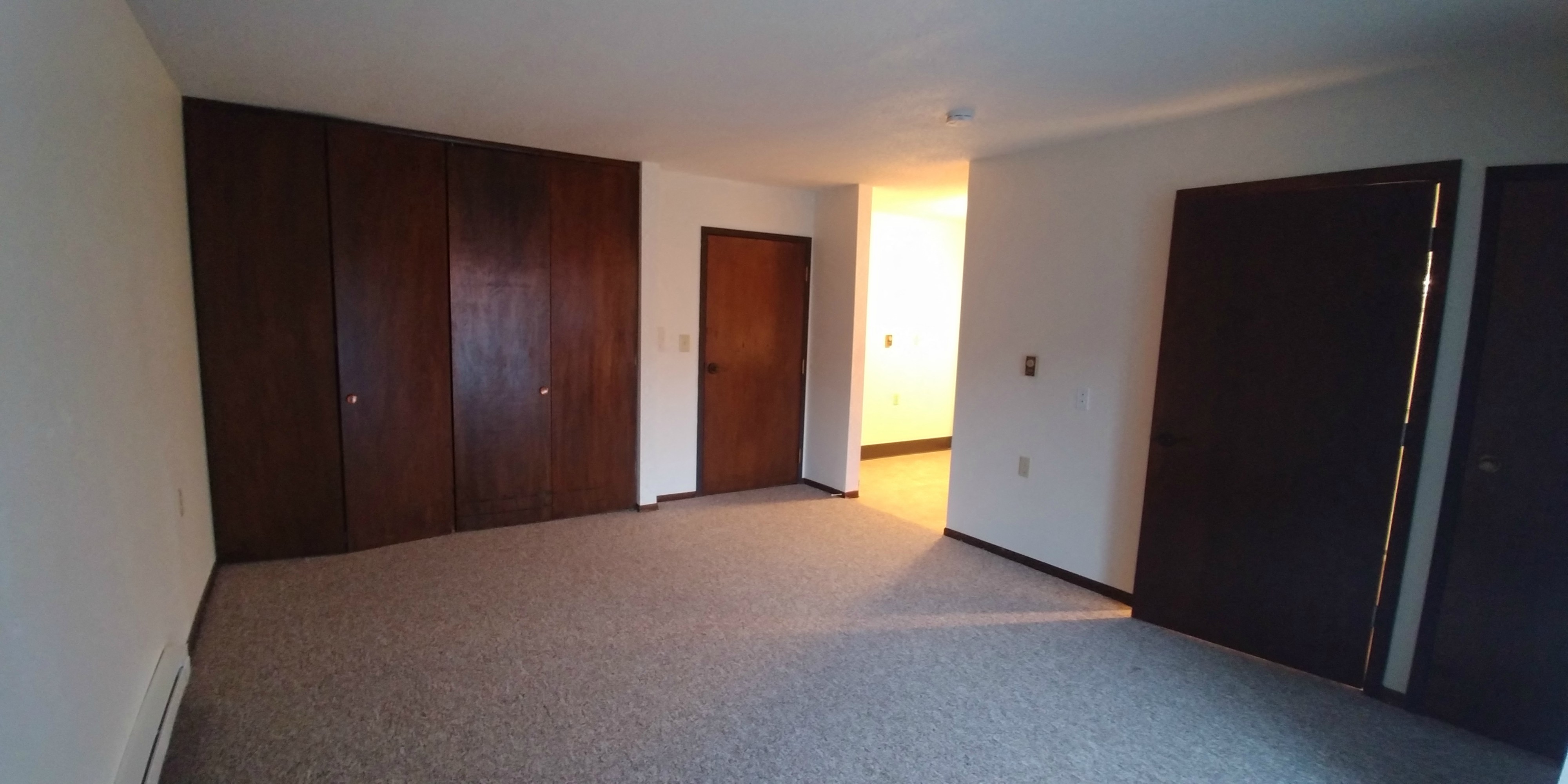 an empty living room with wooden doors and a carpeted floor