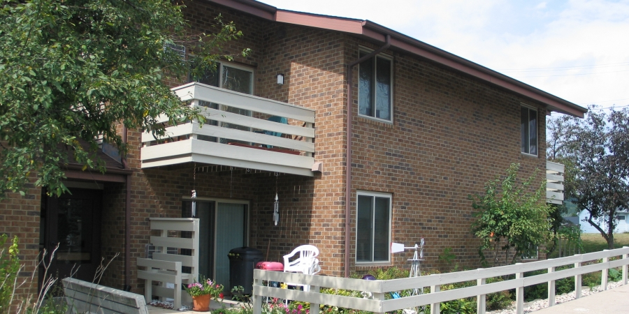 a brick house with two balconies and a white fence