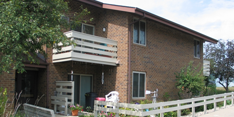 a brick house with two balconies and a white fence