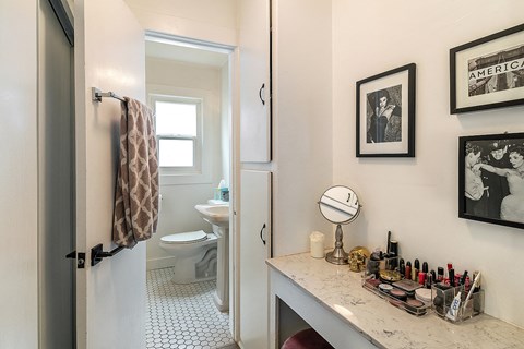 a bathroom with a toilet and a vanity with cosmetics and a mirror