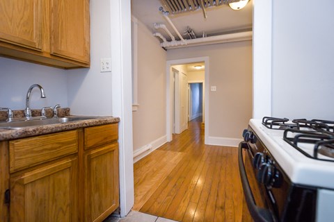 a kitchen with a stove and sink and a hallway with a door to a room