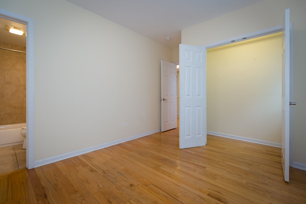 a bedroom with a white door and a wood floor