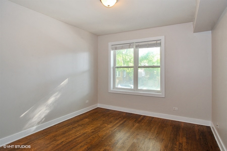 an empty bedroom with wood floors and a window