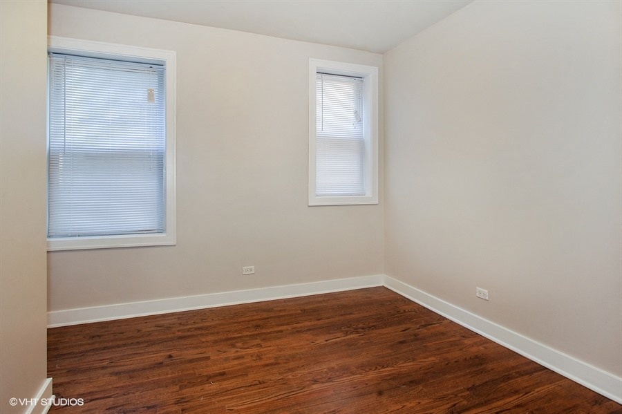 an empty room with a hard wood floor and two windows