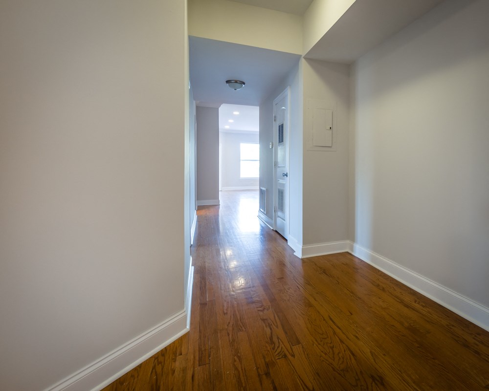 an empty living room and hallway with wood floors and white walls