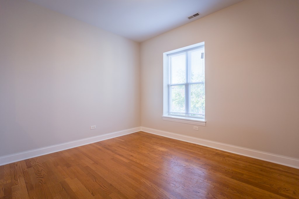 an empty room with wooden floors and a window
