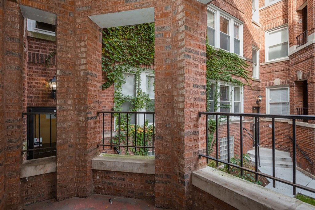 the front of a brick apartment building with a balcony and a window