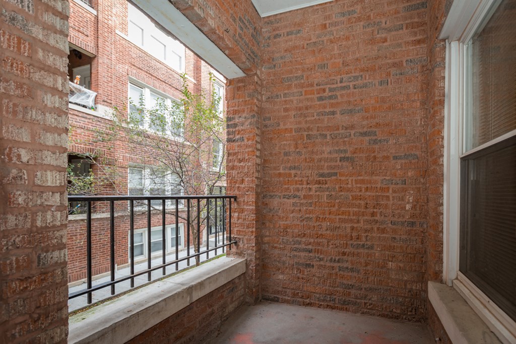 the small balcony has a metal railing and a brick wall