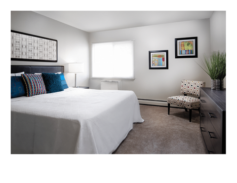 A bedroom with a large bed and a chair.