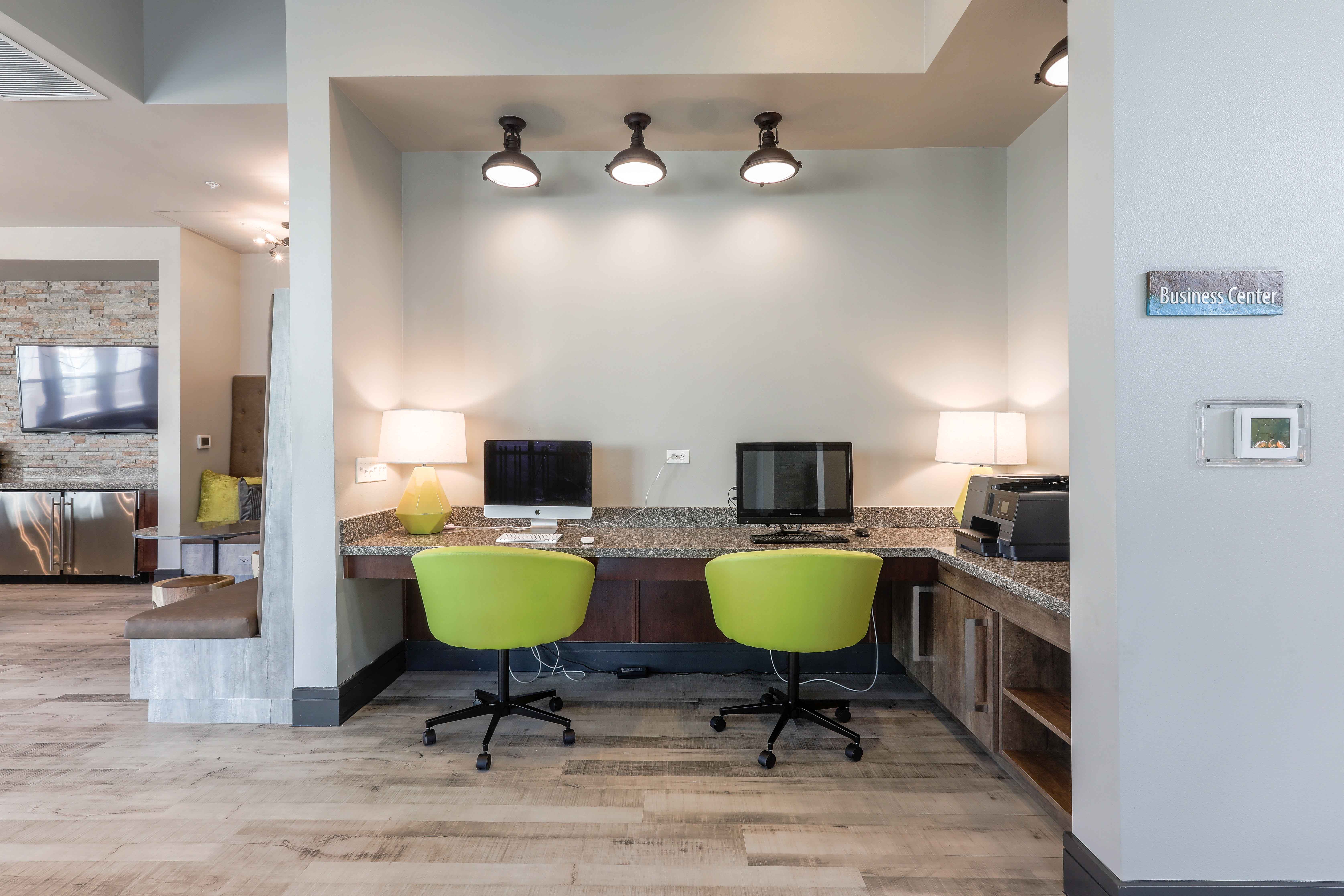 a office with two computers and a desk with green chairs