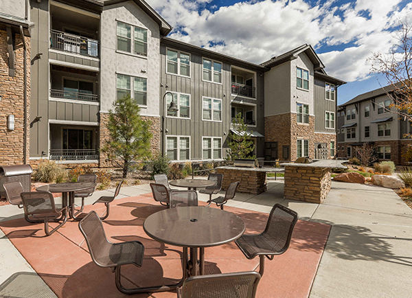 an outdoor patio with tables and chairs in front of an apartment building