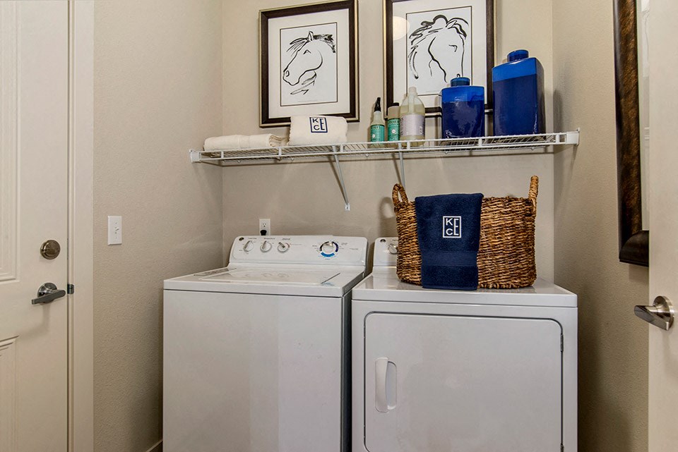 A bathroom with two white washing machines and a basket on top of one.
