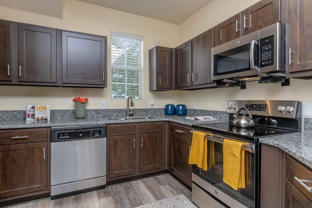 A kitchen with dark brown cabinets and a stainless steel oven.