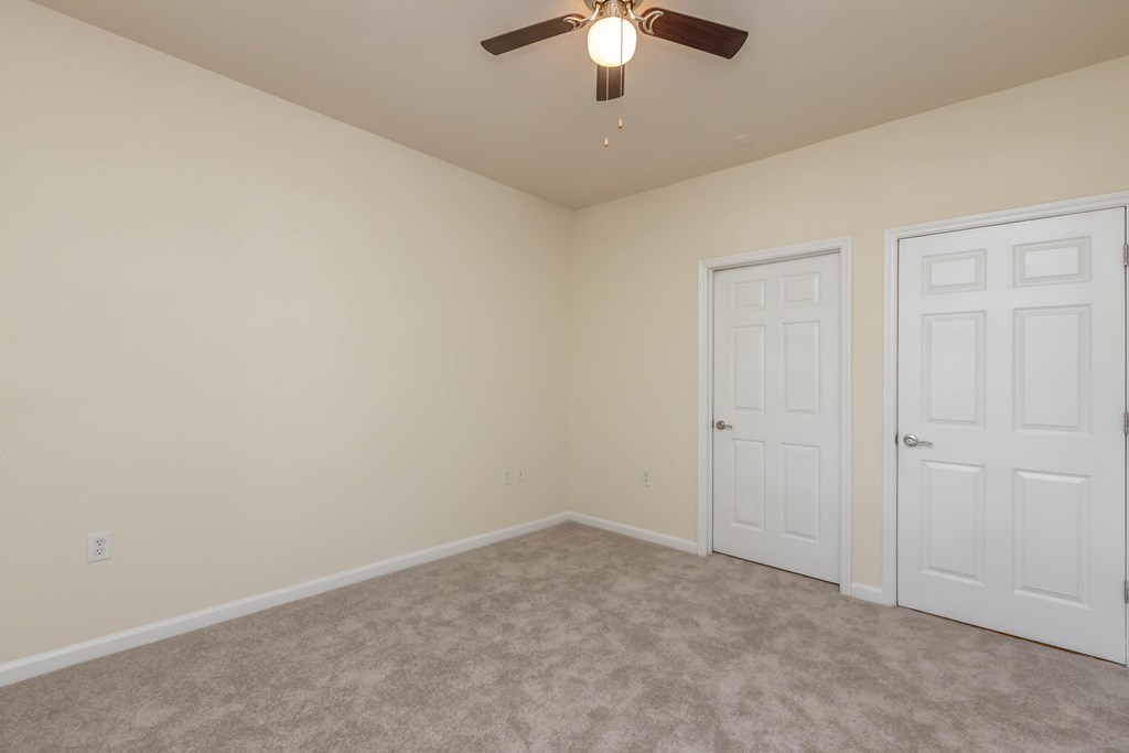 A bedroom with a bed, nightstand, and a ceiling fan.