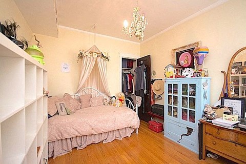 A room with a bed, a dresser, and a chandelier.