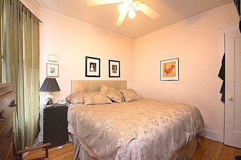 A bedroom with a bed, nightstand, and pictures on the wall.