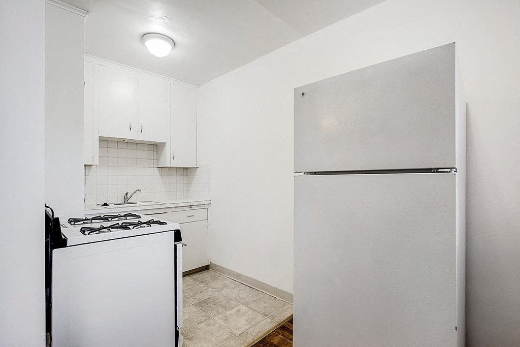 an empty kitchen with a white refrigerator and stove