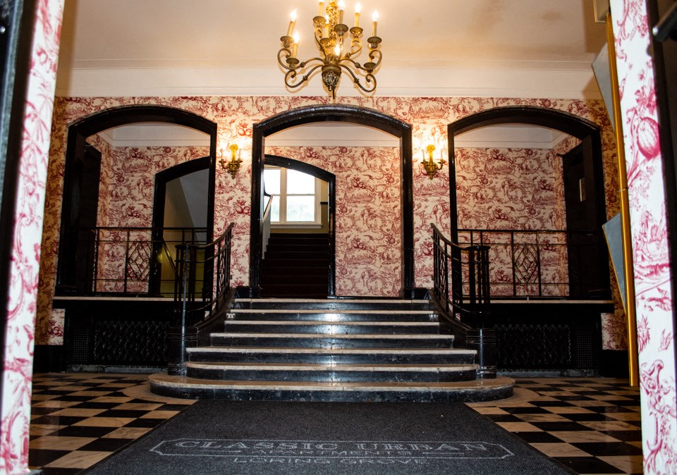 a staircase in a building with a checkered floor and a chandelier