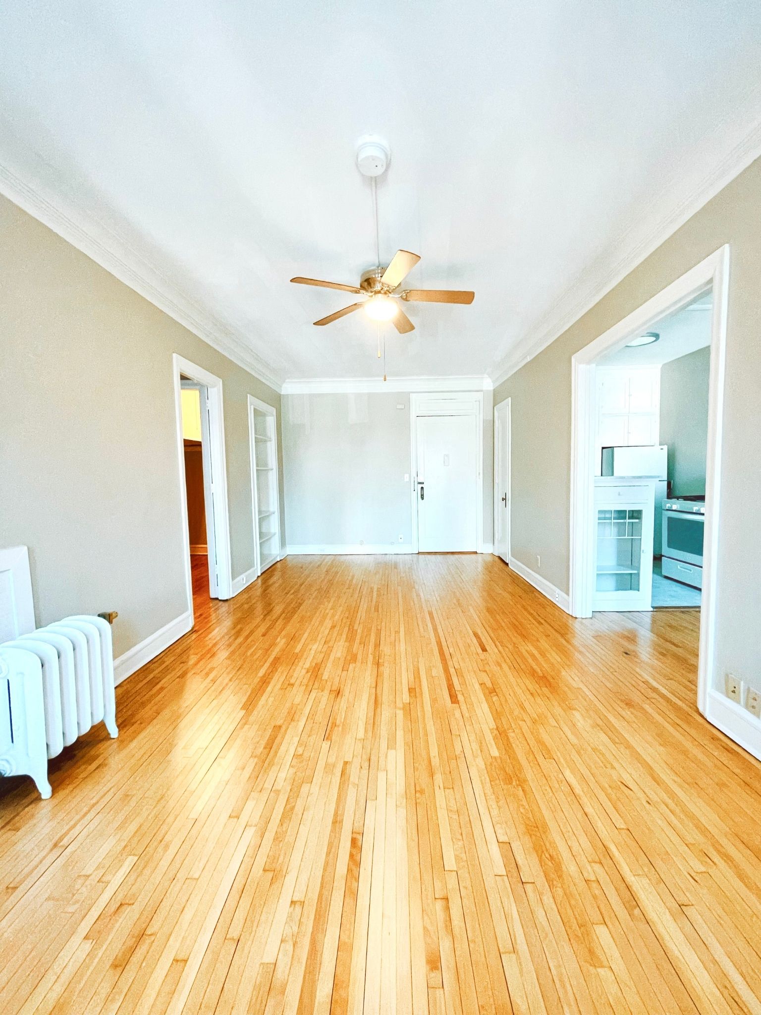 an empty living room with wood floors and a ceiling fan