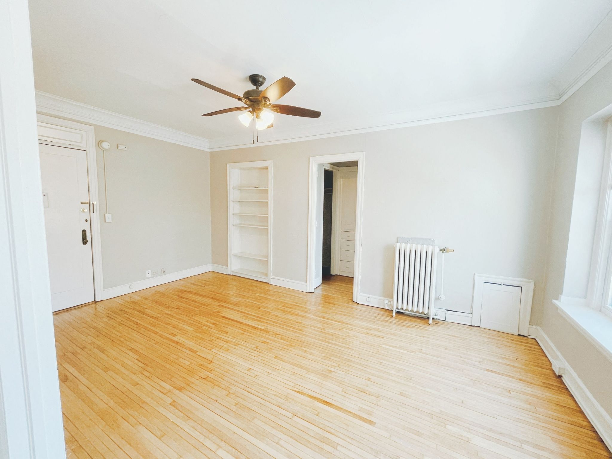 an empty living room with wood floors and a ceiling fan