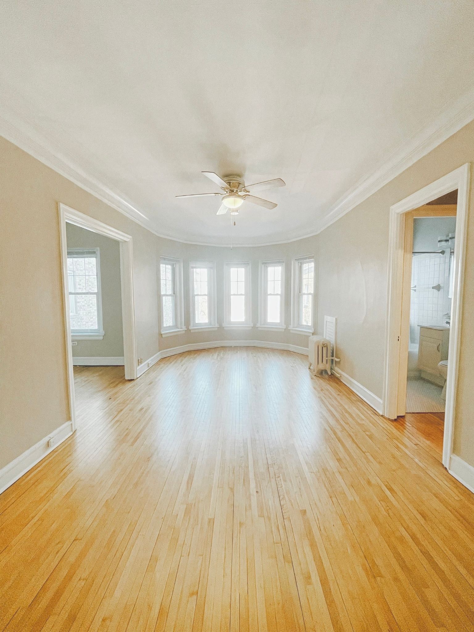 an empty living room with wood floors and a ceiling fan
