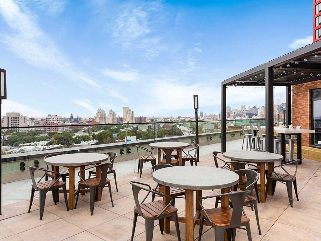 a rooftop terrace with tables and chairs and a view of the city