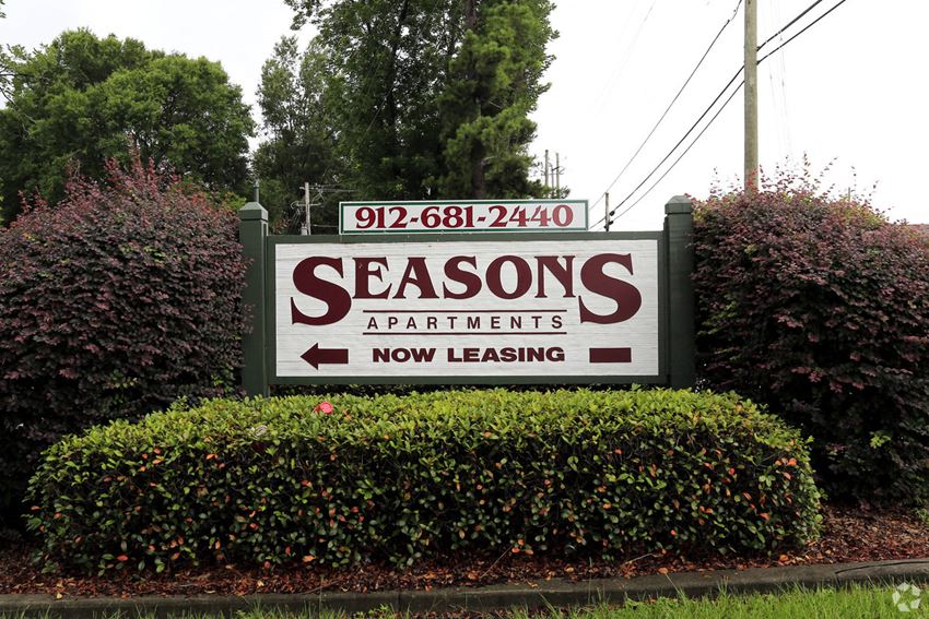 a sign for the seasons apartments on the side of a road