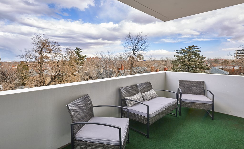 a balcony with three chairs and a view of the city