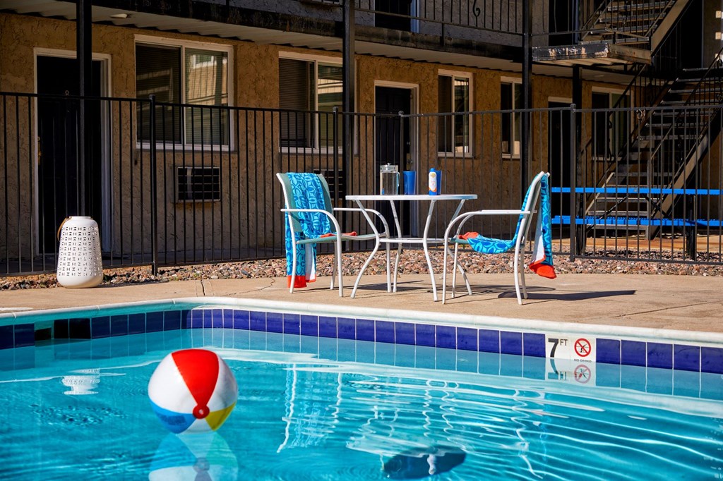 a swimming pool with a table and chairs and a ball in the water