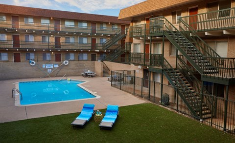 a building with a pool and two lounge chairs in front of it