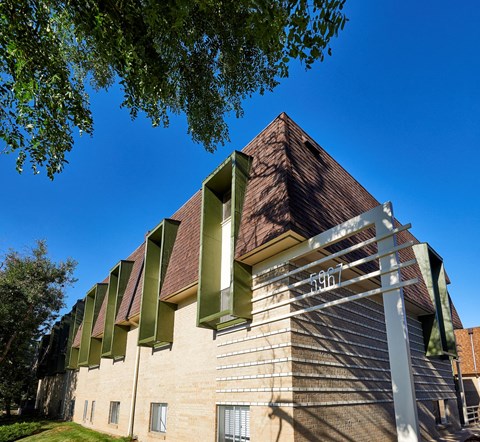 a brick building with green shutters and a blue sky